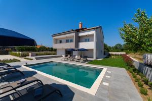 a swimming pool in front of a house at MY DALMATIA - Villa Campi Dalmatia with private heated pool and sauna in Galovac