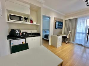 Una habitación con cocina y una habitación con escritorio. en Flat Conforto Andar Alto c/ Varanda | The Palace, en São Paulo