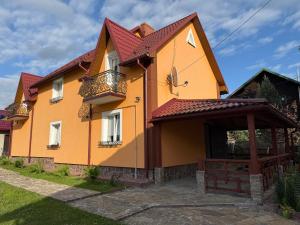 een geel en oranje huis met een rood dak bij ViLLA KUMANETS in Skhidnitsa