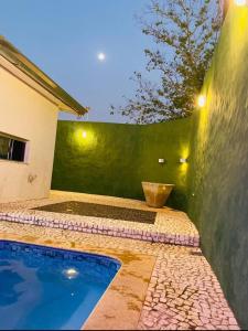 a backyard with a swimming pool and a green wall at Mais Motel e Hotel in Parapuã