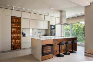 a kitchen with white cabinets and a island with bar stools at Maneo Lux in Poreč