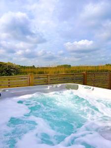 a hot tub on a deck with a fence at Footpath Cottages 