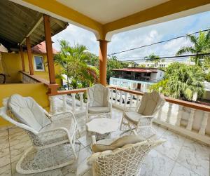 a balcony with white chairs and tables and palm trees at Apartmenthotel Michaela in Sosúa