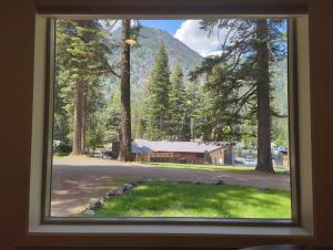 a window with a view of a barn and mountains at Eagle Cap Chalets in Joseph