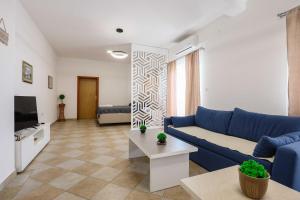 a living room with a blue couch and a tv at Apartment with Pool "Sunset Cove" in Neum