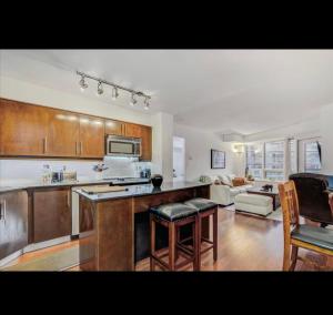a kitchen with wooden cabinets and a living room at Core Downtown Toronto-8 Sleeper-4 Beds-2 Bathrooms-Washrooms-Free Parking-CN Tower-Ripleys Museum-Blue Jays Stadium In front-Indoor Gym-Swimming Pool-Jacuzzi Sauna-Filter Drinking Water-WiFi in Toronto