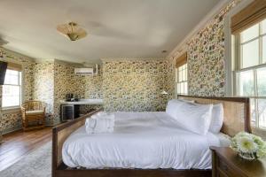 een slaapkamer met een groot wit bed met bloemenbehang bij The Nicholas Veranda King Suite - Walk to King in Charleston