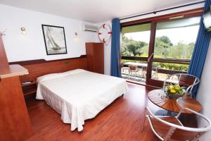 a bedroom with a bed and a table and a window at Residence Castell'Verde in Porto-Vecchio