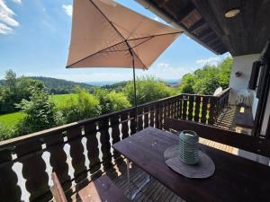 a picnic table on a deck with an umbrella at d' Aussicht nach LA in Deggendorf