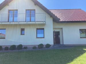 a white house with a porch and a balcony at Sielska Chatka in Sarbinowo