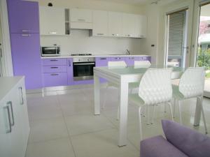 een keuken met paarse kasten en een witte tafel en stoelen bij Appartamento Costa Azzurra in Grado