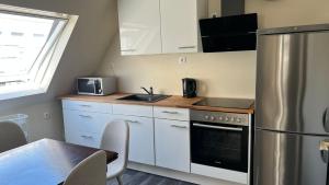 a kitchen with white cabinets and a table and a refrigerator at Marlin City Apartment 2 in Bielefeld