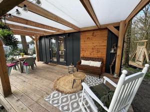 a patio with a couch and a table and chairs at Tiny forest lodge with direct access to forest and nature in Anloo