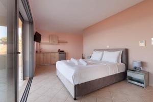 a bedroom with a large white bed and a kitchen at Ground Floor Studio by the sea in Monemvasia