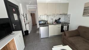 a small kitchen with white cabinets and a couch at Olympiada Complex Calma Di Mare Apartment in Ofrínion
