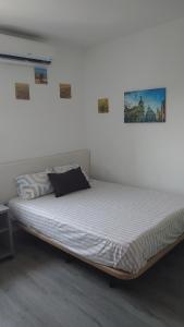 a bed in a room with two pictures on the wall at Apartamento de 3 habitaciones in Getafe
