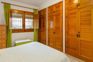 a bedroom with wooden cabinets and a white bed at Chalet Monterrey in Real de Gandía +7 photos