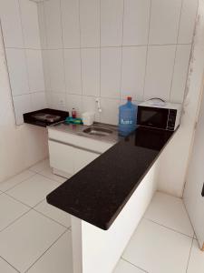 a small white kitchen with a black counter top at Nox Temporada Flat Completo em Caruaru com Ar e Wi-Fi Flat 101 in Caruaru +17 photos