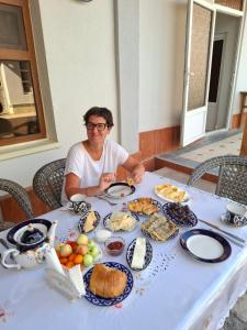 a woman sitting at a table full of food at Arabon Guest House in Bukhara
