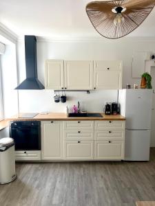 Una cocina con gabinetes blancos y un refrigerador blanco. en Le refuge urbain - T2 à la gare, en Rennes