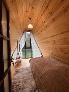 a bedroom with a bed in a wooden room at Lunea Cottage in Itʼkhvisi