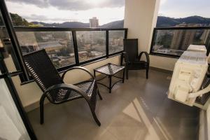 a balcony with two chairs and a table and windows at Flats Diamond - Conforto, ed.novo e moderno localização impar in São Lourenço