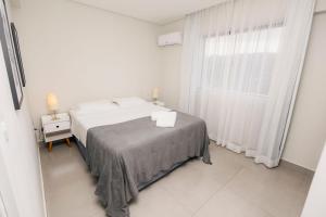 a white bedroom with a bed and a window at Flats Diamond - Conforto, ed.novo e moderno localização impar in São Lourenço