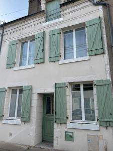 ein Gebäude mit grünen Rollläden und einer Tür in der Unterkunft Chez Laurette Les Montils Maison de Bourg in Les Montils