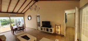 a living room with a television and a dining room at Charmante maison de plain pied rénovée et climatisée en lisière de forêt in Saint-Jean-de-Monts