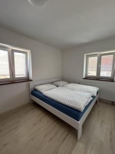 a bedroom with a bed in a room with two windows at Apartmán Vrbno in Kadov +7 photos