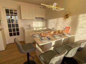 a kitchen with a table with plates and chairs at Le Paradis Fort Mahon, vue mer, élégance et fraîchement rénové in Fort-Mahon-Plage