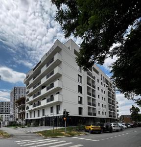 a white building on a city street with a yellow car at Monarch Luxury Apartment in Timişoara
