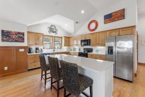 a kitchen with wooden cabinets and a large island with bar chairs at CNU At The Beach in Kill Devil Hills