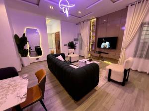 a living room with a black couch and a tv at Four bedroom Luxury house Lekki in Lekki