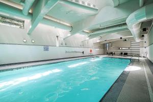 a large swimming pool with blue water in a building at Downtown Condo with Great City Views in Vancouver