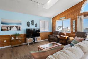 a living room with a couch and a tv at Coasties Ocean Breeze in Kill Devil Hills