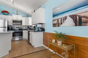 a kitchen with white cabinets and a blue wall at Coasties Ocean Breeze in Kill Devil Hills