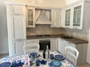 une cuisine avec des armoires blanches et une table et des chaises dans l'établissement Il Gelsomino, à Mommio