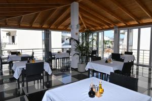 a restaurant with white tables and chairs and windows at Hotel Marku in Ksamil