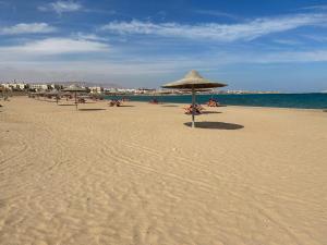 a beach with umbrellas and people sitting on the sand at Chalet Amexico Paradise - Ain Sokhna familys only in Az Za‘farānah