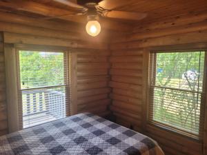 una camera da letto con un letto e due finestre in una baita di tronchi di Hidden Cove - Beauty On The Lake! a Oscoda