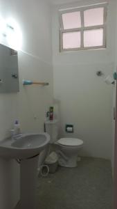 a bathroom with a toilet and a sink and a window at Quartos em Meireles Fortaleza in Fortaleza