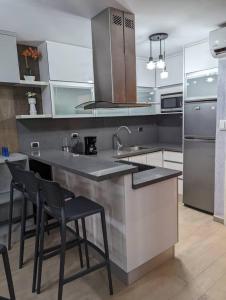 a kitchen with a sink and a counter with chairs at Studio with Amazing Beach view in Porlamar