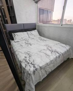 a bed with a white comforter in a room with a window at Studio with Amazing Beach view in Porlamar