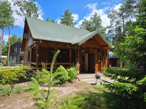 a small wooden house with a green roof at ChillForest SPA in Tomczyn