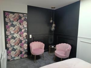 two pink chairs in a room with black walls at Cocon romantique avec jacuzzi extérieur in Rosières-près-Troyes
