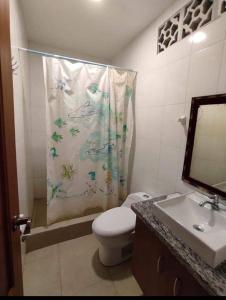ein Badezimmer mit Duschvorhang, Toilette und Waschbecken in der Unterkunft Casa General Villamil, amplia y cerca del mar in Playas