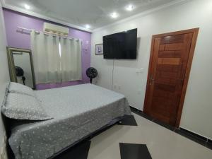 a bedroom with a bed and a flat screen tv at Quarto Privativo Rains Santos in Belém