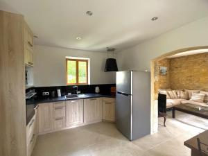 a kitchen with a stainless steel refrigerator and a couch at Le Cottage dans la Vallée des 5 châteaux in Vézac +7 photos