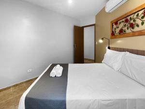 a hotel room with a bed with two shoes on it at 2 quartos - 200m do mar - Jacuzzi - AC - Churrasqueira in Guarujá +39 photos